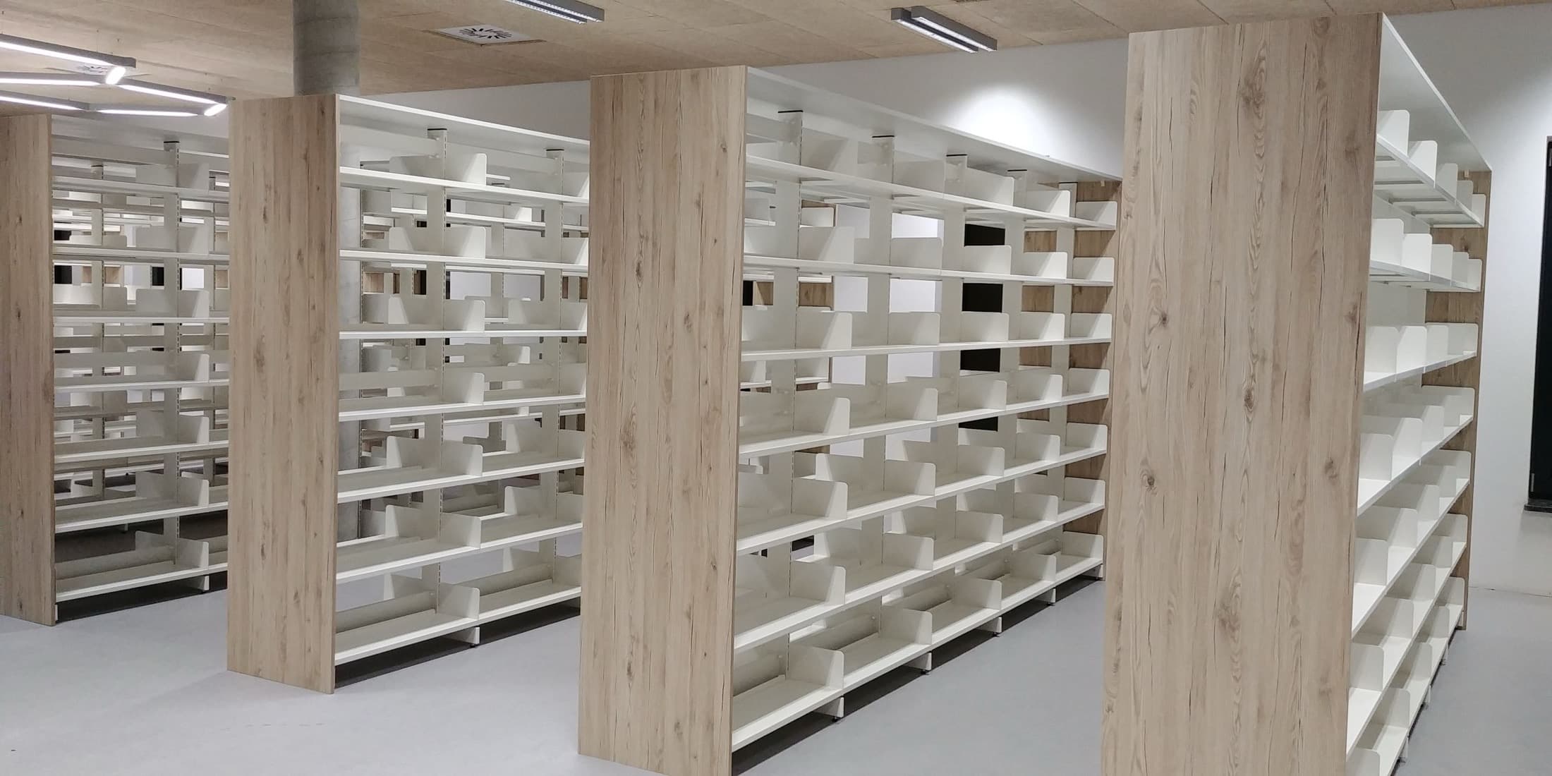 Białe regały biblioteczne z dekoracyjnymi bokami w kolorze jasnego drewna