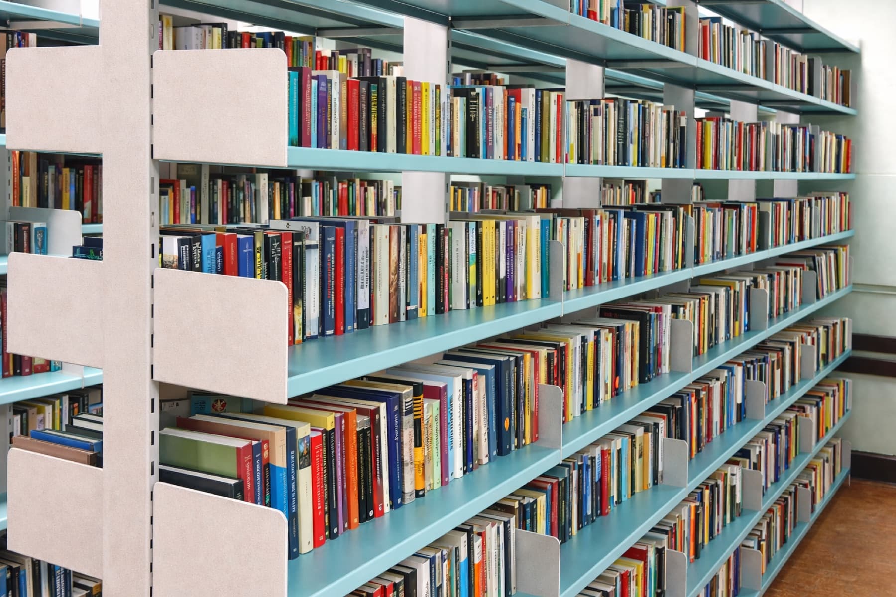 Regały biblioteczne metalowe MITUM wypełnione książkami w bibliotece